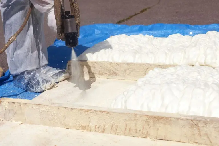Technician dressed in a protective white uniform spraying foam insulation
