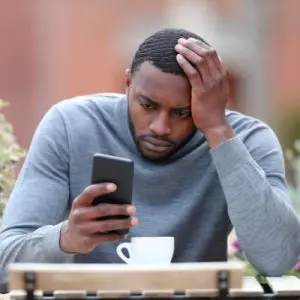 man looking at a ringing phone not answering