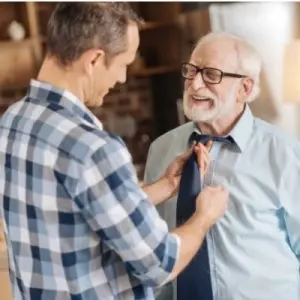 Son dressing dad with dementia
