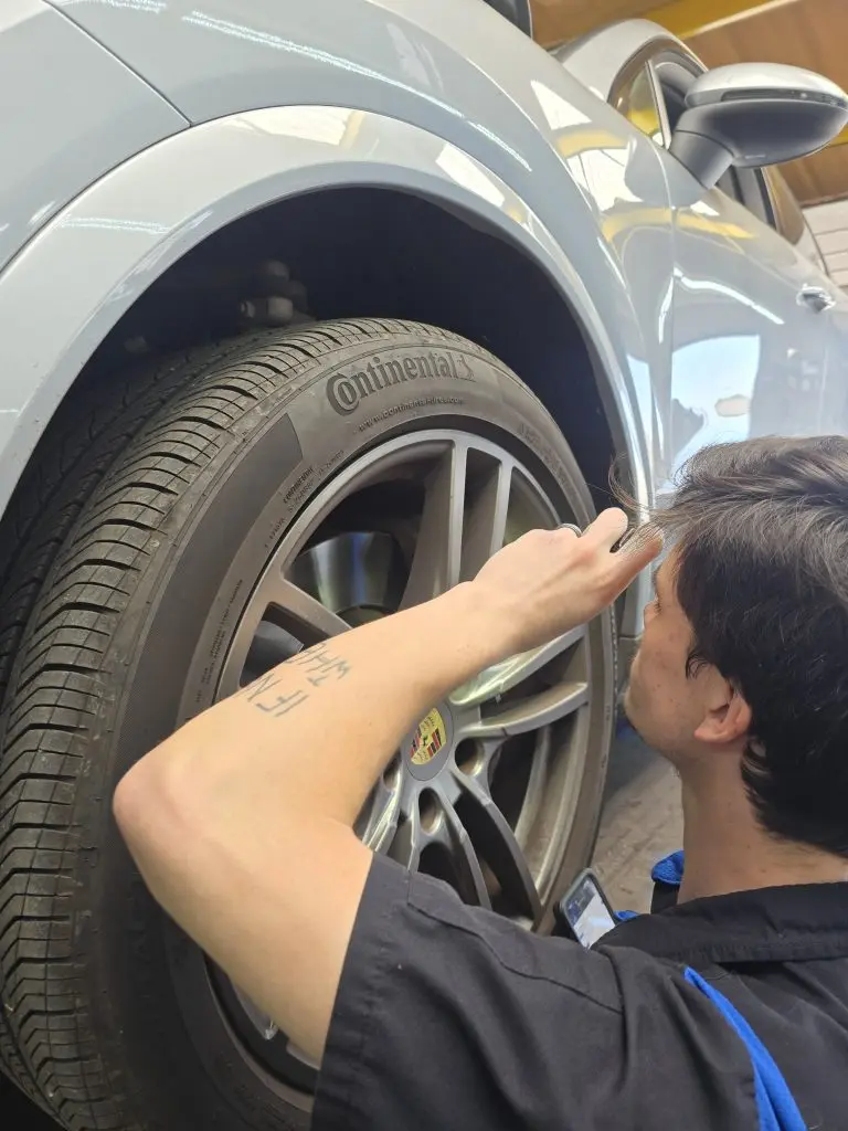 Priebe's Auto Clinic technician performing a tread depth safety check on a car tire in Oklahoma City.