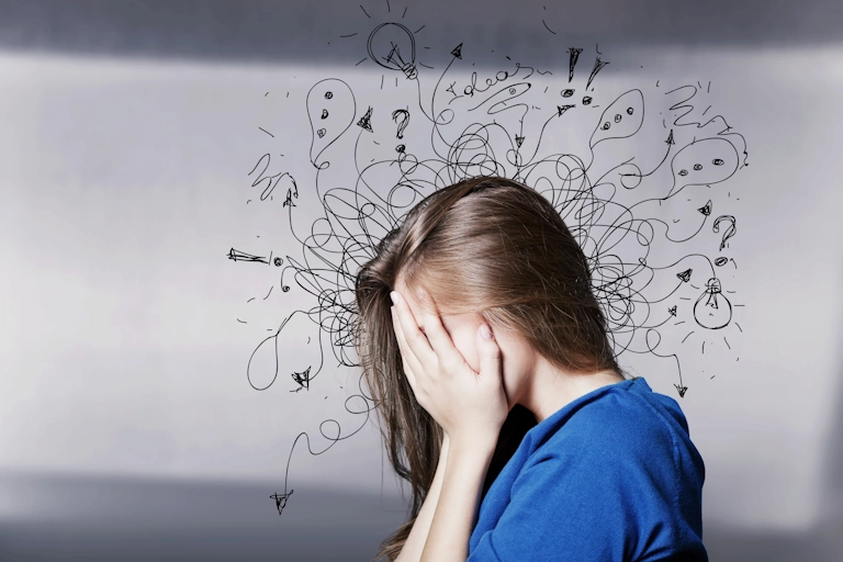 A woman covers her face, overcome with the burden of anxiety
