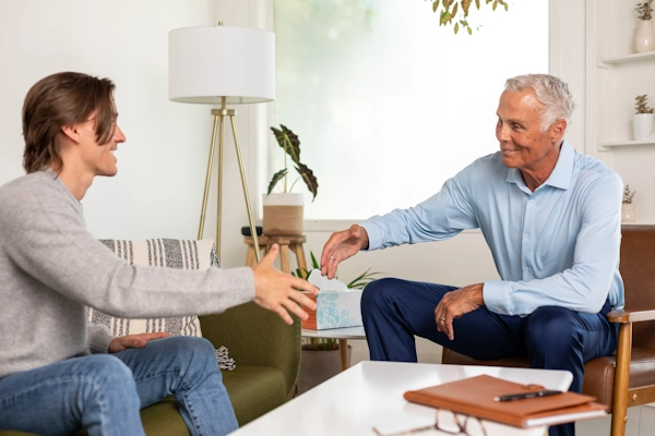Two men smile while participating in anger management counseling