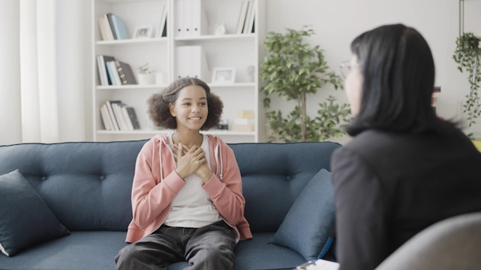 A teenager girl speaks with her therapist during a teen therapy session at Armstrong Family Counseling