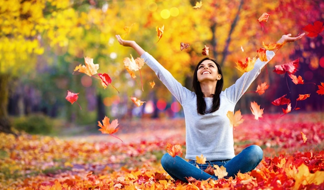 A happy woman celebrates in the beauty of fall leaves