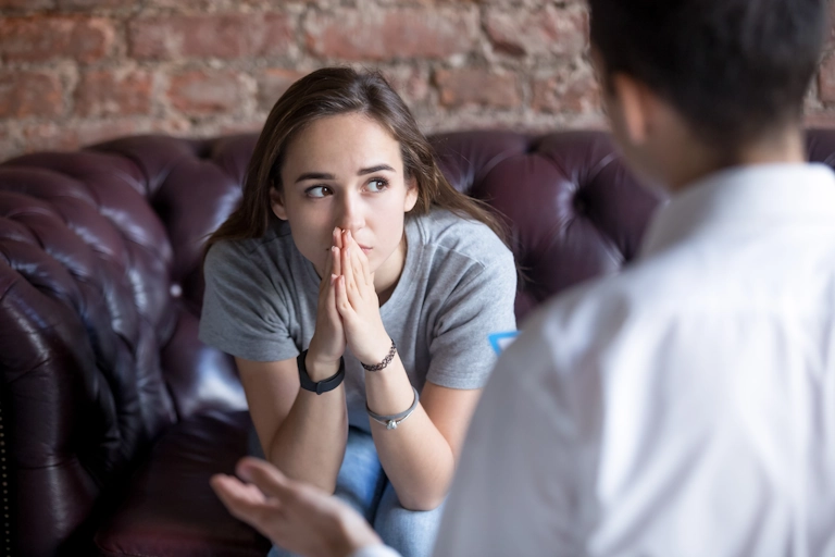 A teen girl struggling with anxiety speaks with a therapist at Armstrong Family Counseling