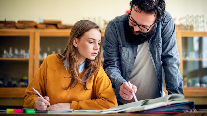 A teacher helps a student with an assignment