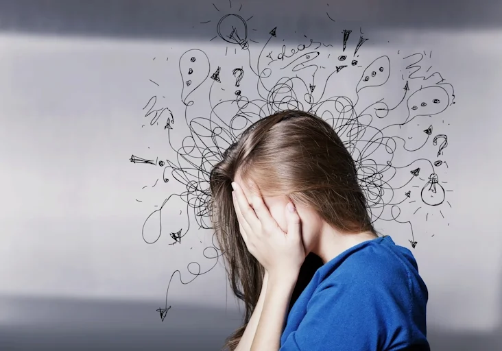 A woman covers her face, overcome with the burden of anxiety
