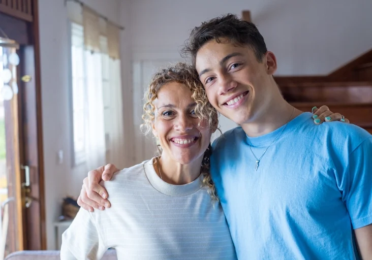 A mom and son smile and hug after family counseling