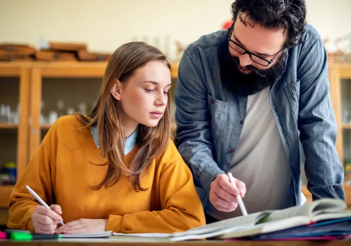 A teacher helps a student with an assignment