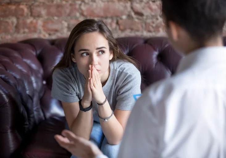A teen girl struggling with anxiety speaks with a therapist at Armstrong Family Counseling