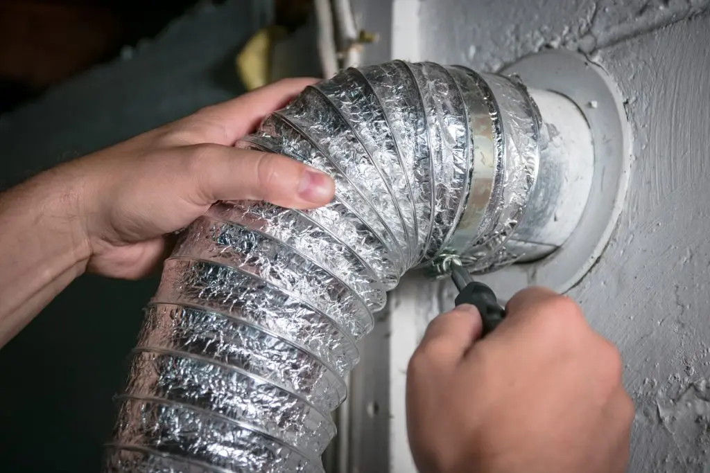 Person securing a flexible dryer vent hose with a clamp