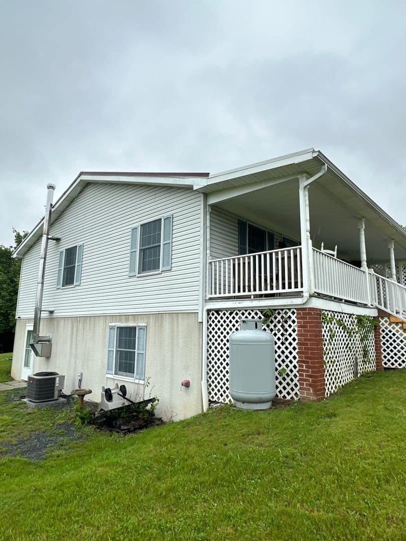 pro pressure works cleaning a house with a white vinyl siding and maintaining the surrounding lawn and landscaping