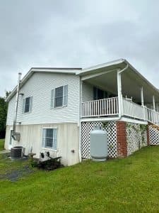 pro pressure works cleaning a house with a white vinyl siding and maintaining the surrounding lawn and landscaping