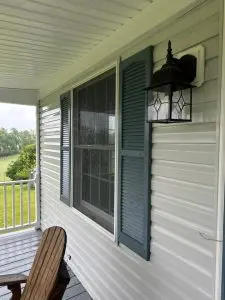 house washing being done on vinyl siding with clean sections visible and a porch light installed near the window
