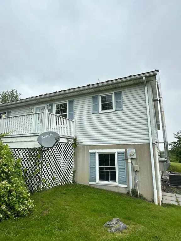 pro pressure works cleaning a light blue vinyl siding with green grass and a lattice fence in the foreground