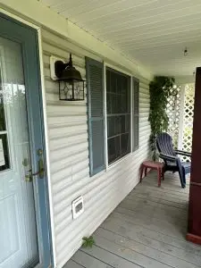 cleaning of a porch area with vinyl siding and a wooden deck using pressure washing techniques