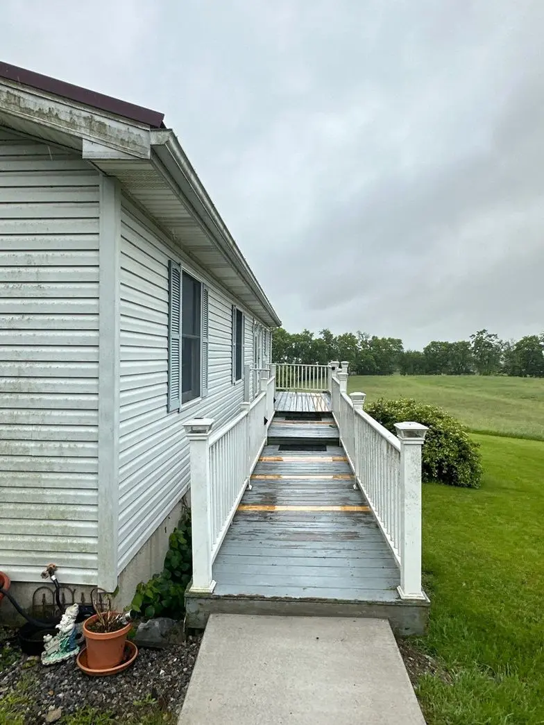deck cleaning on a residential home with visible dirt and algae on the surface and cloudy sky in the background