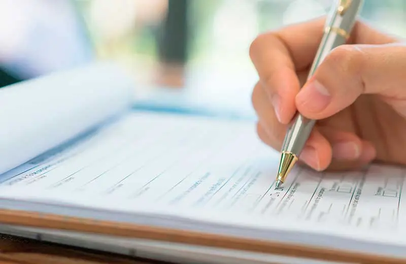 Hand filling out new patient health history form for McCracken Chiropractic.