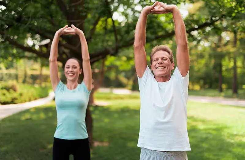 Man and woman stretching outdoors for back pain relief and chiropractic care.
