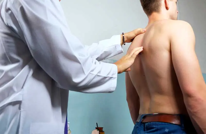 Chiropractor assessing patient's posture and spine during screening.
