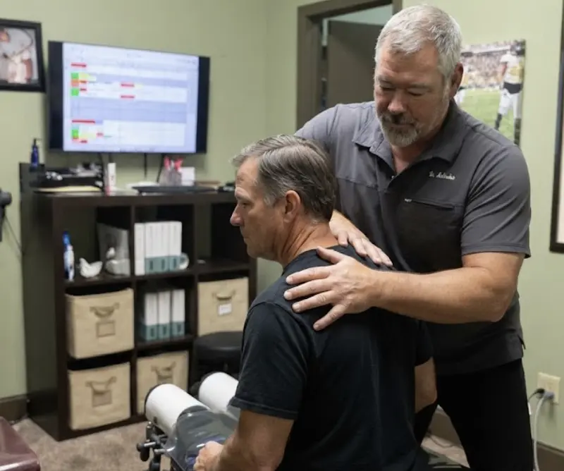 Dr. Chris McCracken examining a patient's upper back and shoulders at McCracken Chiropractic in Calhoun, GA.