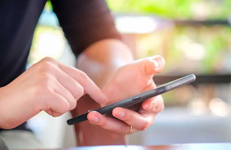 Hands holding smartphone scheduling chiropractic screening at McCracken Chiropractic.