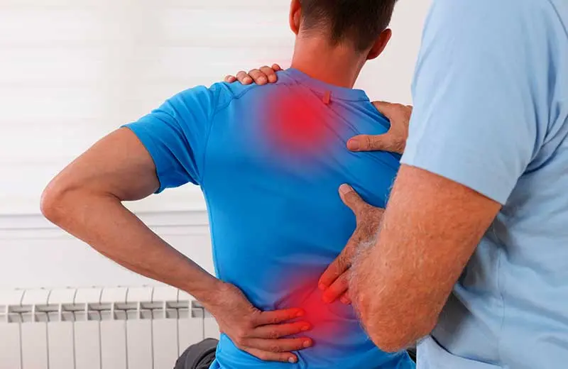 Man experiencing back pain and chiropractor assessment for spinal decompression treatment.