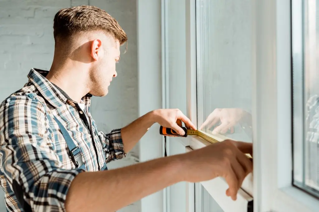 close up of homeowner measuring replacement windows in home