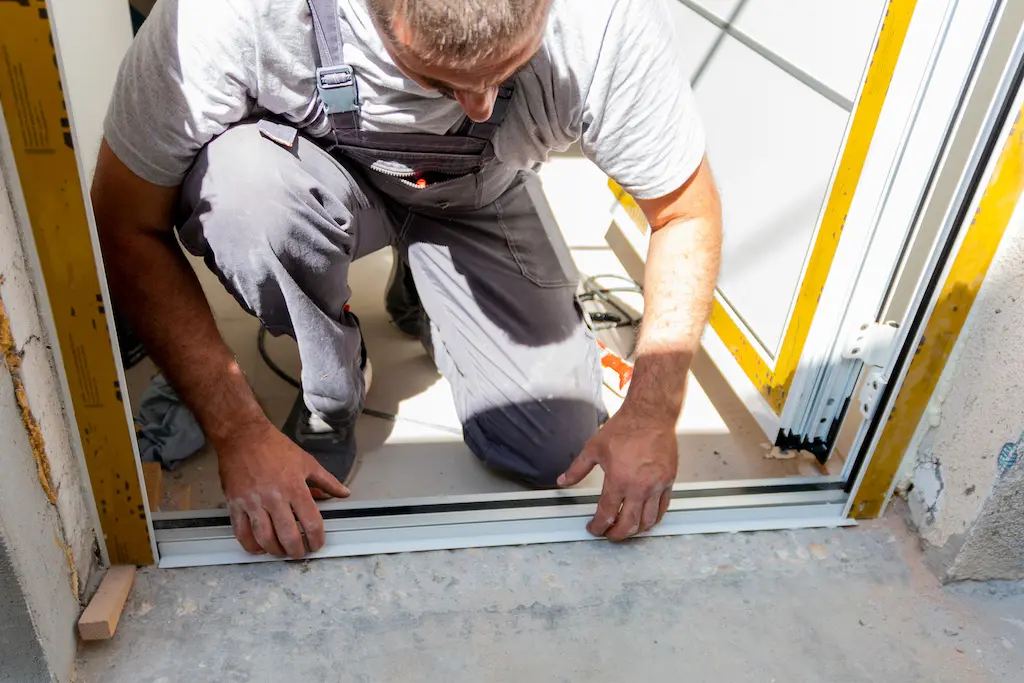 perform a door frame replacement Professional carpenters installing an entrance door in a new apartment. Door installation worker replaced the old one with a new one