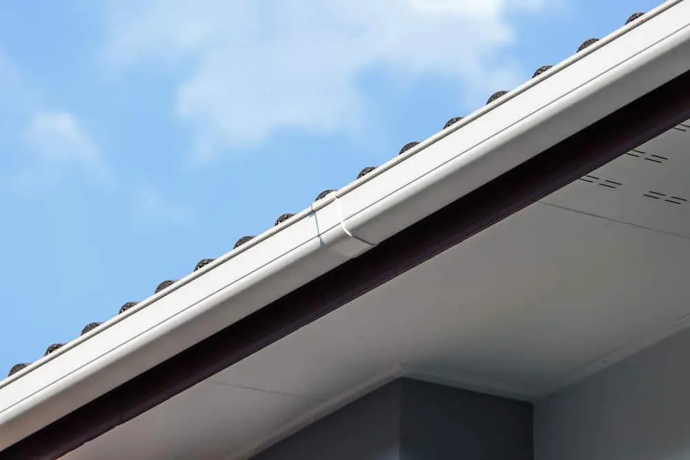 White gutter installed along the rooftop edge of a house