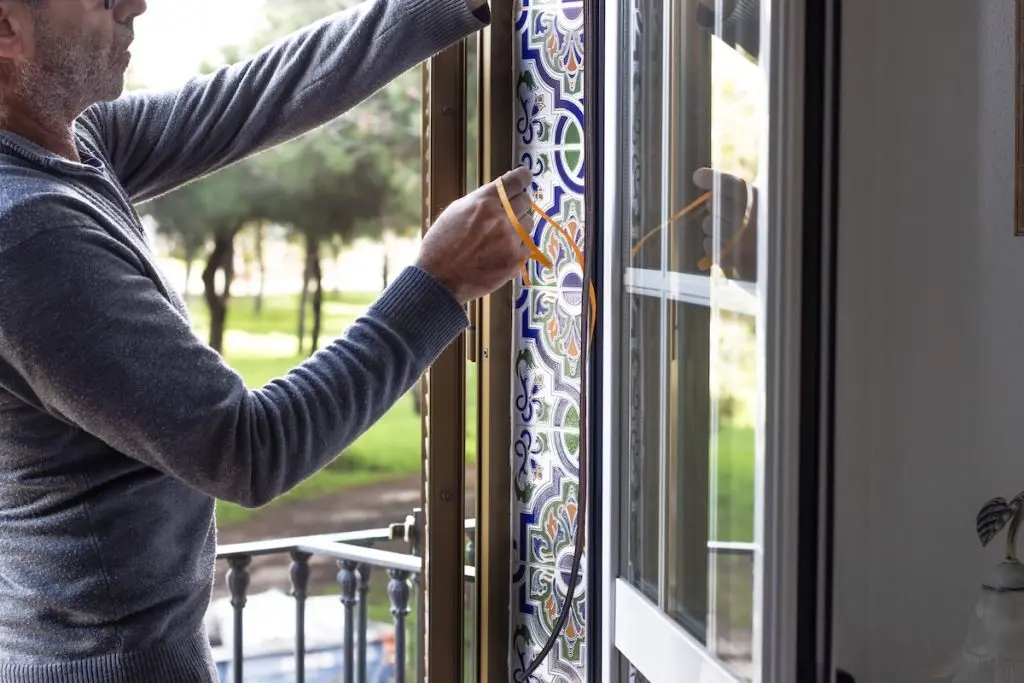 exterior door weatherstripping types Man installing weatherstripping on a window frame to improve insulation and prevent drafts. Home maintenance, energy efficiency, and DIY repair concept in a bright interior. exterior door weatherstripping types