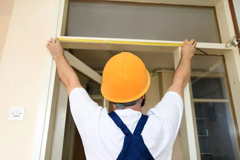how to measure for a new front door Construction worker and handyman is working on renovation of apartment. Builder is measuring of room door using measure tape at construction site. Renovation concept. Construction and service tools.