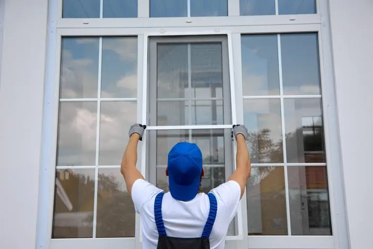 Background of blue-cap worker installing a mosquito net on large plastic window outside the building in summer. Professional installation of an additional insect net on window
