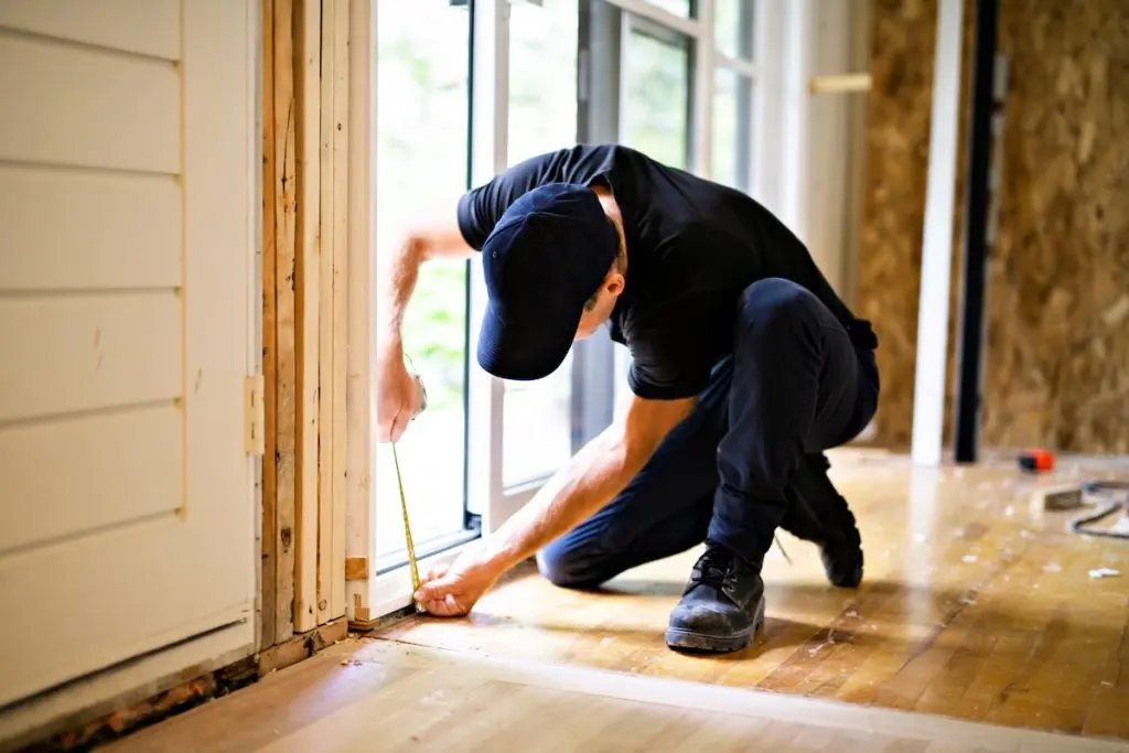  handsome young man installing Double Sliding Patio Door in a new house construction site window repair cost