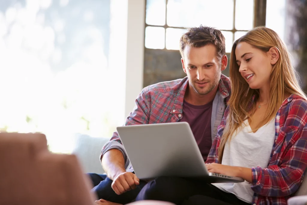couple on computer finalize replacement windows after measuring old ones