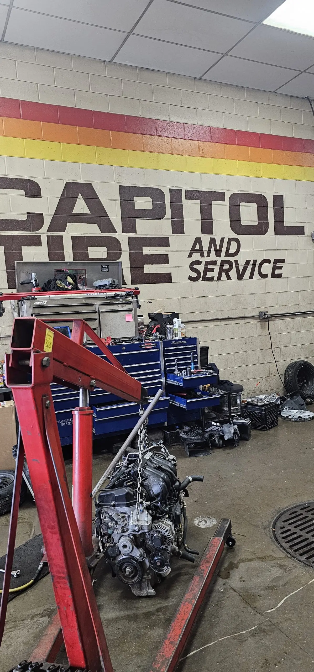 Engine pulled and hanging on a red engine hoist on the shop floor of Capitol Tire and Service