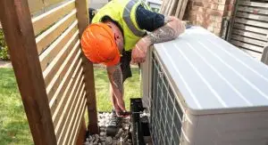 A-1 Comfort Care technician in safety gear performing maintenance on an outdoor HVAC unit