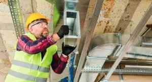 a technician installing HVAC ductwork in a ceiling