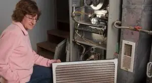 woman inspecting a furnace and air filter
