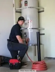 A happy water heater installation technician draining a water heater.