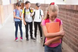 Pupils friends teasing a pupil alone in elementary school
