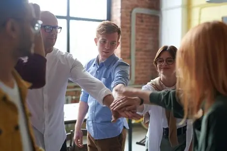 6ways4 | Search Strategy Marketing People in an office joining hands.