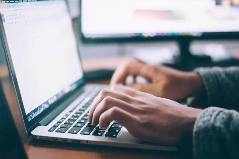 a man's hands shown typing on a laptop