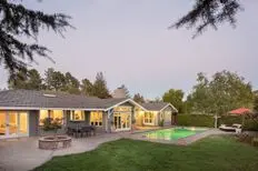 Luxury home with beautiful landscaping, including a swimming pool at sunset