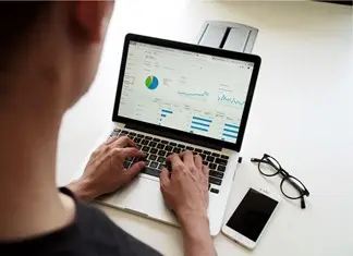 A man using his laptop for data aggregation in marketing.