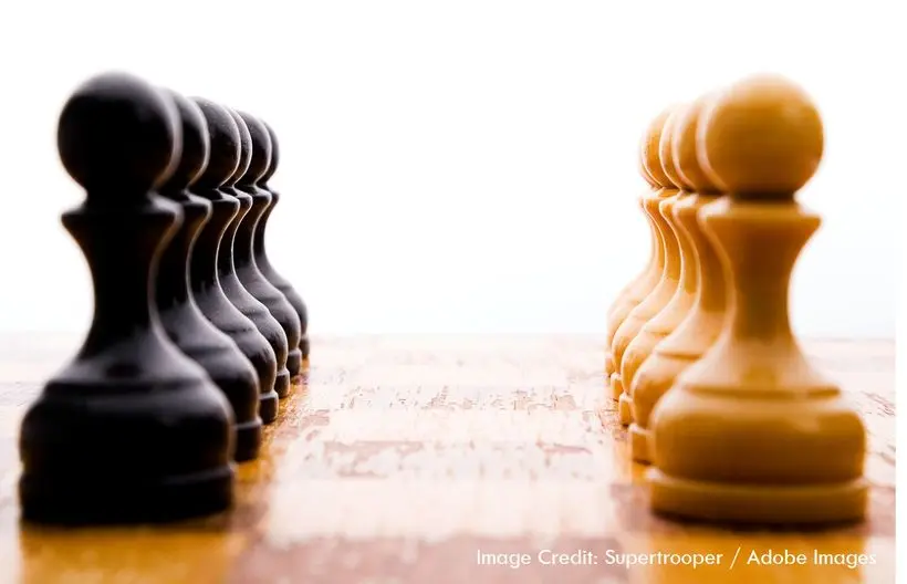 black pawns lined up on the left and tan pawns lined up on the right on a chess board