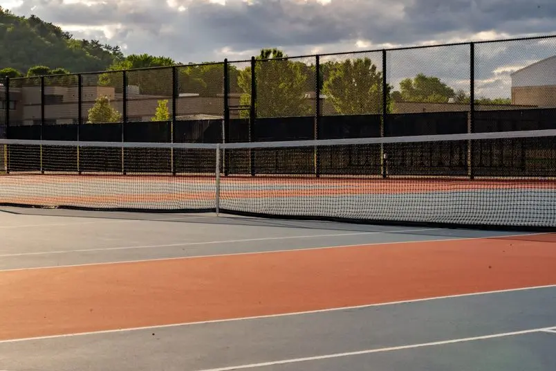 AdobeStock_513656582 | Search Strategy Marketing a beautiful tennis court with a high fence surrounding it. Search Strategy helps fence contractors with their marketing needs.