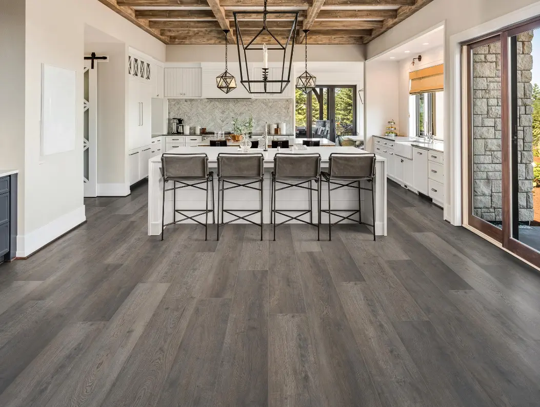 Modern kitchen featuring Longfellow laminate flooring from the AquaProof collection, showcasing textured 7.7" planks in a rich, dark shade, complemented by contemporary cabinetry and pendant lighting.