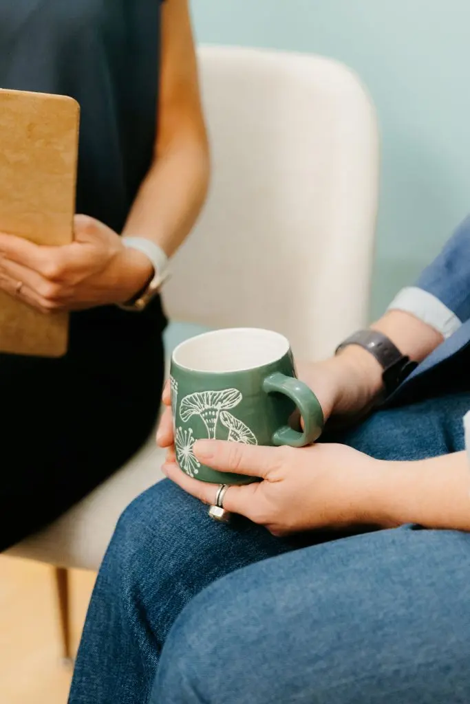 Dr. Aidanne holding a clipboard while a patient holds a mug of tea.