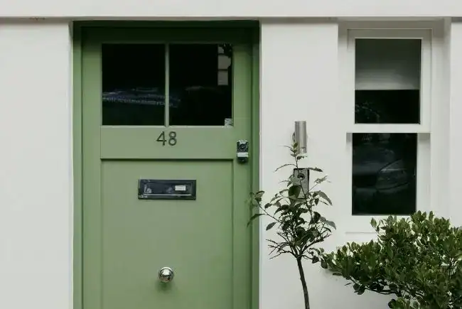 green front door against a white wall.